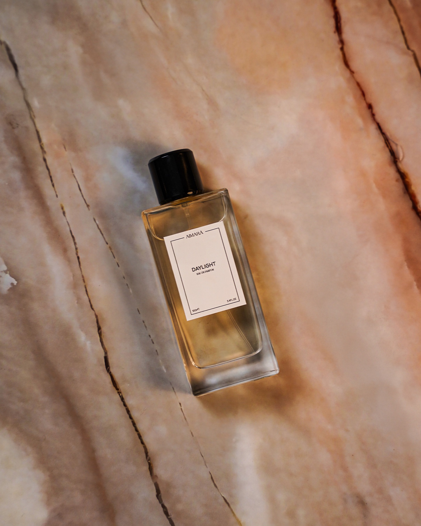 Luxury perfume bottle photographed on a warm textured stone surface for fragrance product photography.